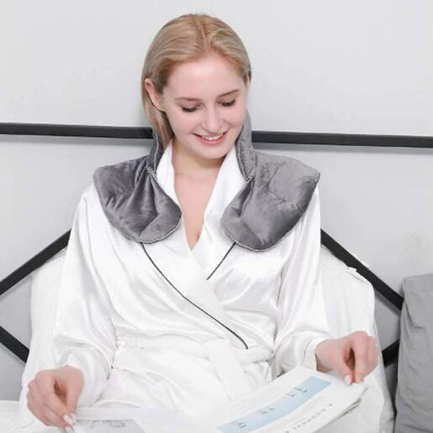 Femme lisant avec un coussin chauffant aux graines de lin sur les épaules