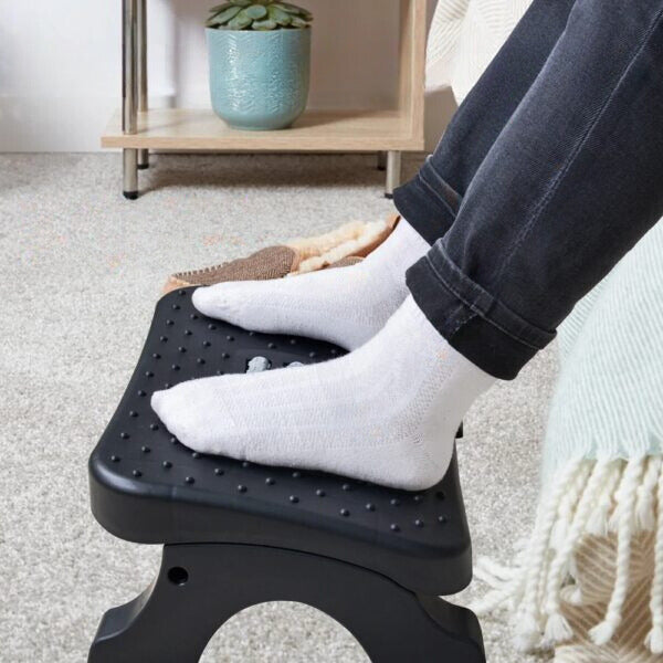 Personne utilisant le repose-pieds de bureau ErgoStance™ pour surélever ses jambes et améliorer sa posture assise.