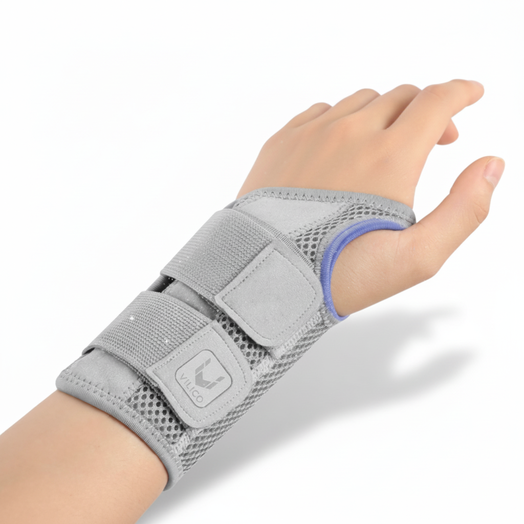 Gros plan sur l'attelle de poignet CarpaGuard™ grise portée sur une main gauche, montrant le tissu respirant en maille et les deux sangles de serrage ajustables.