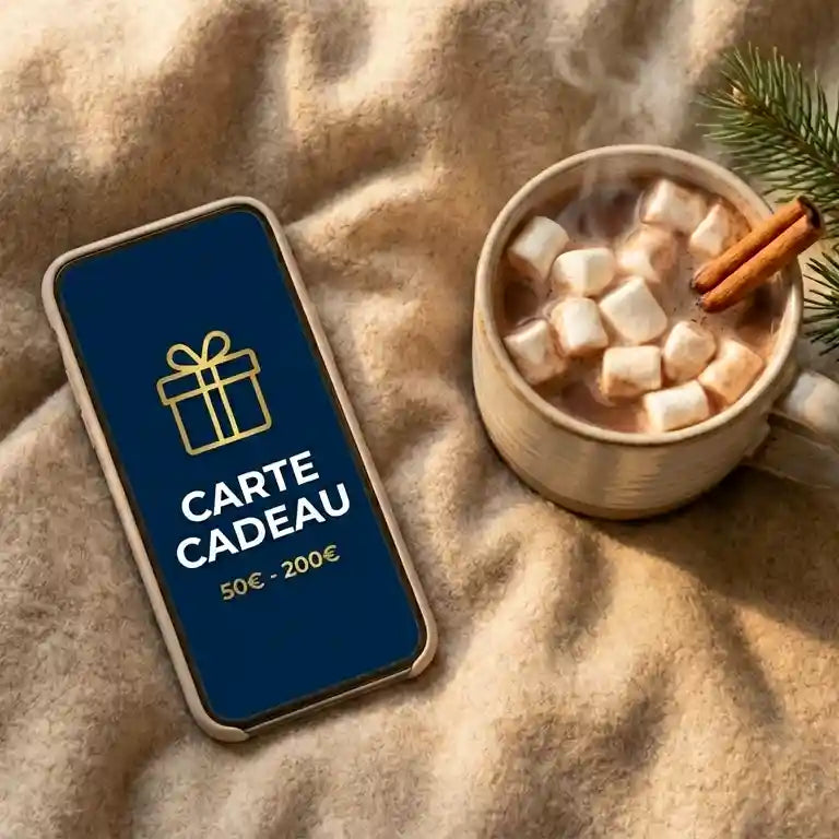Carte cadeau digitale affichée sur un smartphone, ambiance hivernale avec chocolat chaud, réception immédiate par email.