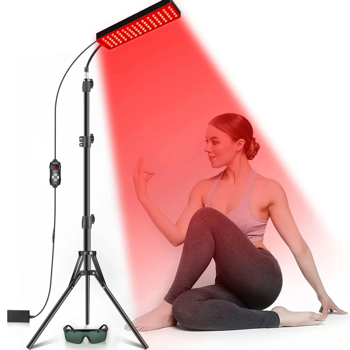 Femme pratiquant le yoga sous la lumière d'un panneau de thérapie par lumière rouge et infrarouge sur trépied.