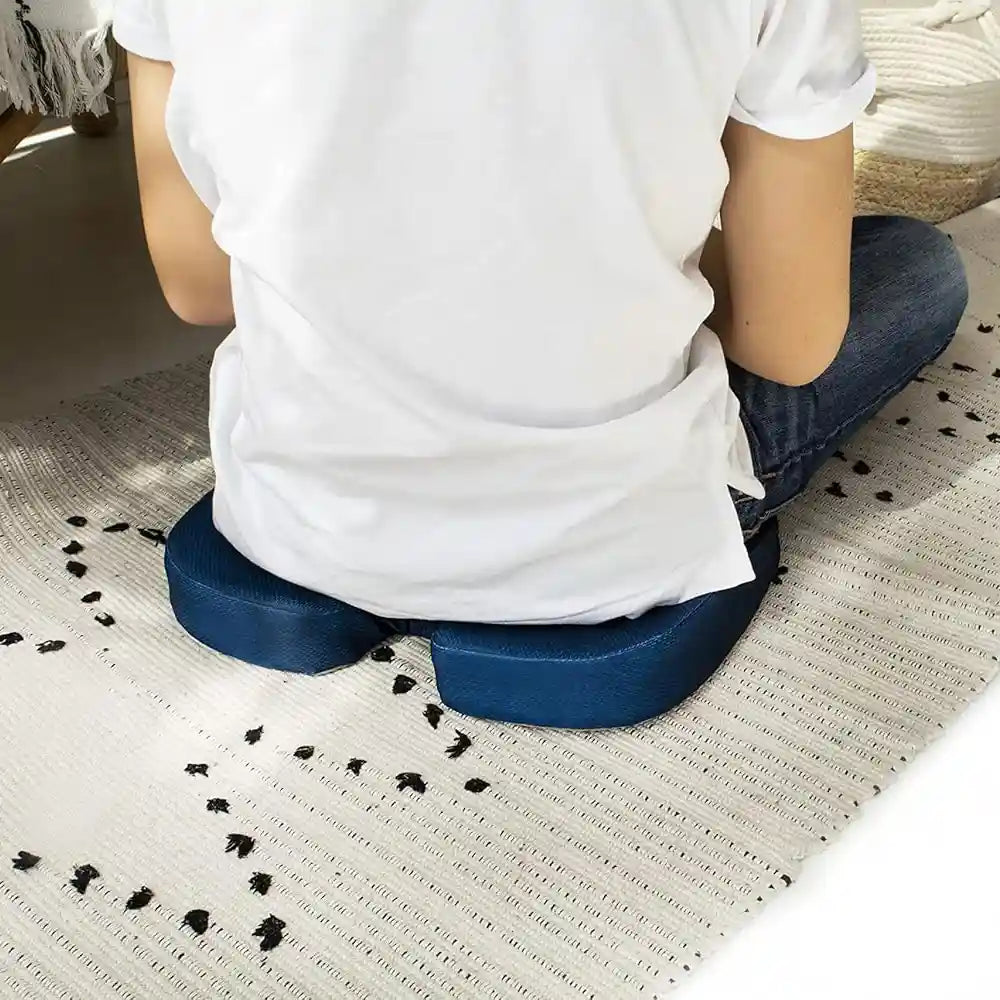 Personne assise sur un coussin ergonomique coccyx bleu