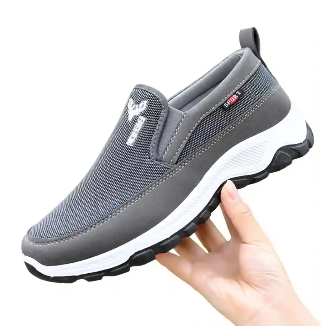 Chaussure orthopédique grise pour homme en tissu respirant, tenue en main pour montrer la légèreté et la flexibilité de la semelle.