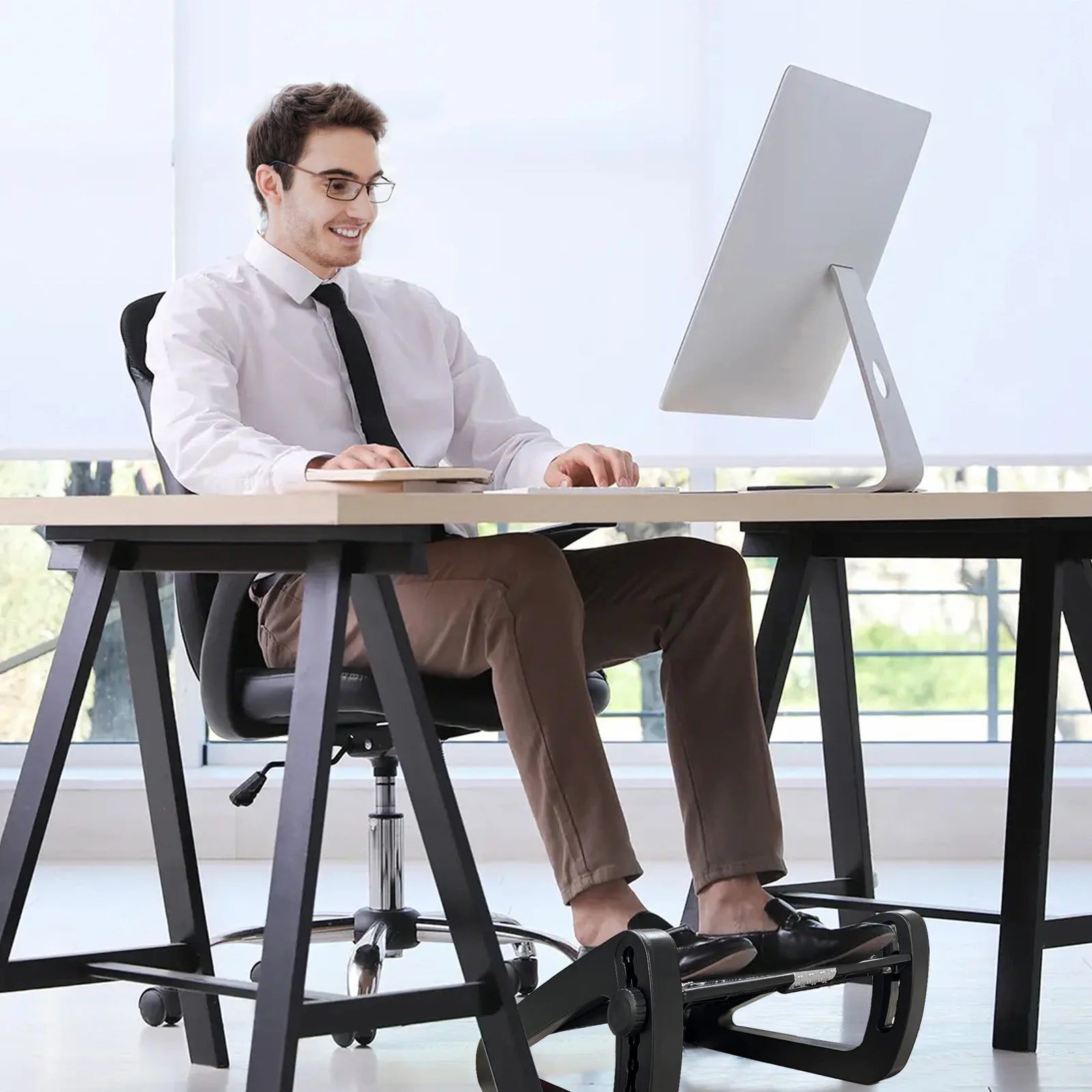 Homme travaillant à son bureau avec une posture améliorée grâce au repose-pieds ergonomique ErgoStance™ qui soutient ses jambes.