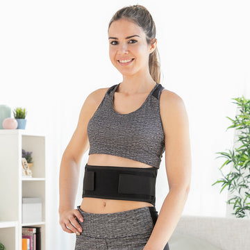 Femme portant la ceinture lombaire chauffante ThermoBelt sous ses vêtements de sport pour un soutien dorsal discret.