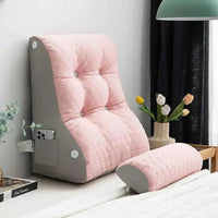 Dossier incliné matelassé rose avec poche latérale et coussin cylindrique posé sur un lit